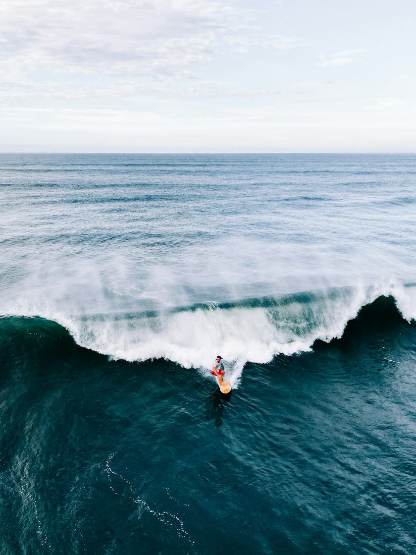 Vista desde arriba de un surfista bajando por la pared de una ola
